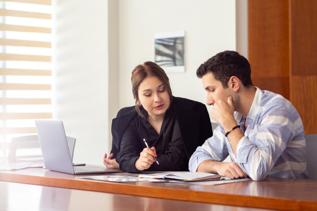 front view young beautiful businesswoman black shirt black jacket along with young man discussing work issues inside her office work job building